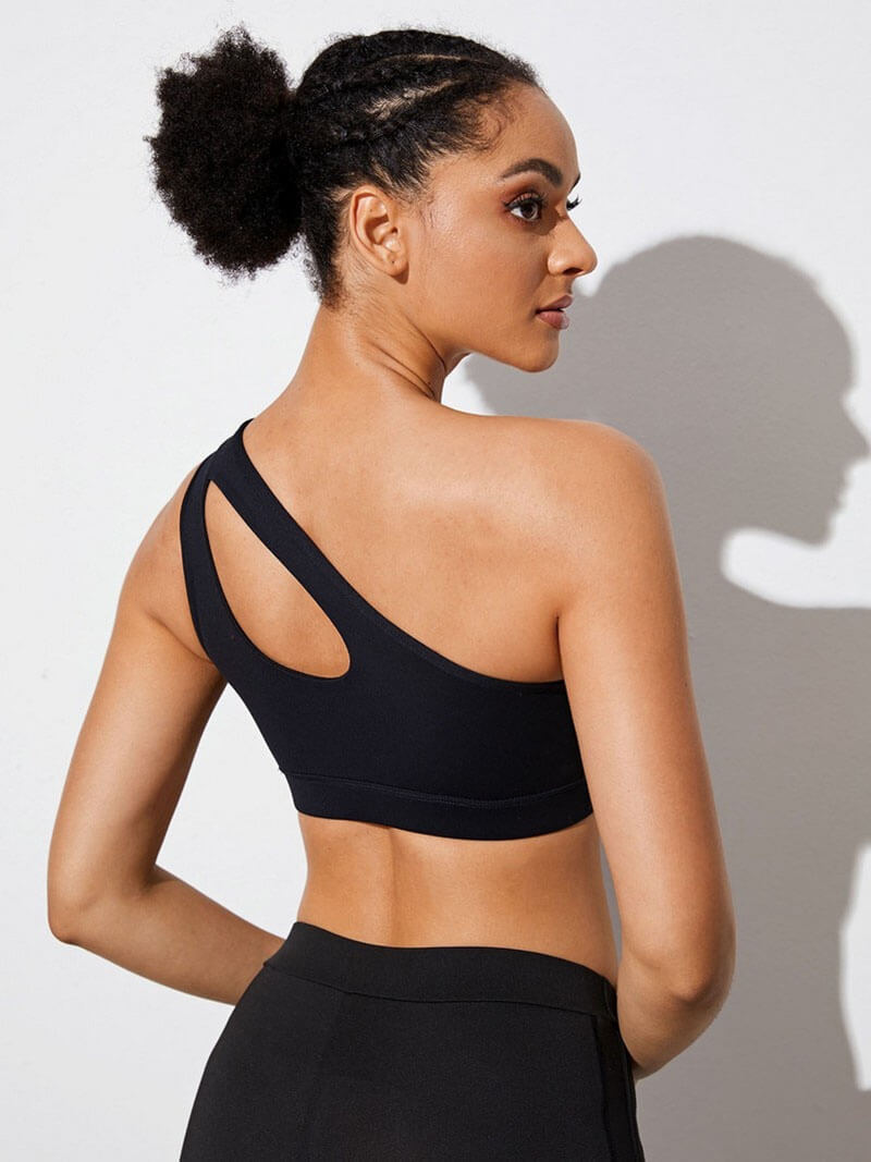 Woman wearing a stylish one-shoulder black sports bra for fitness, highlighting comfort and breathability.